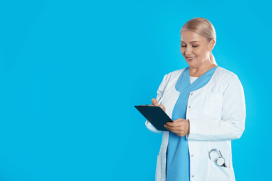 Photo of Mature doctor with clipboard on blue background. Space for text