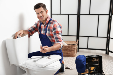 Photo of Professional plumber working with toilet bowl in bathroom