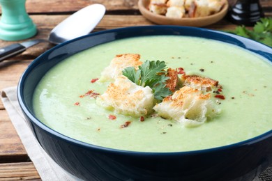 Delicious asparagus soup with croutons and parsley in bowl on table, closeup