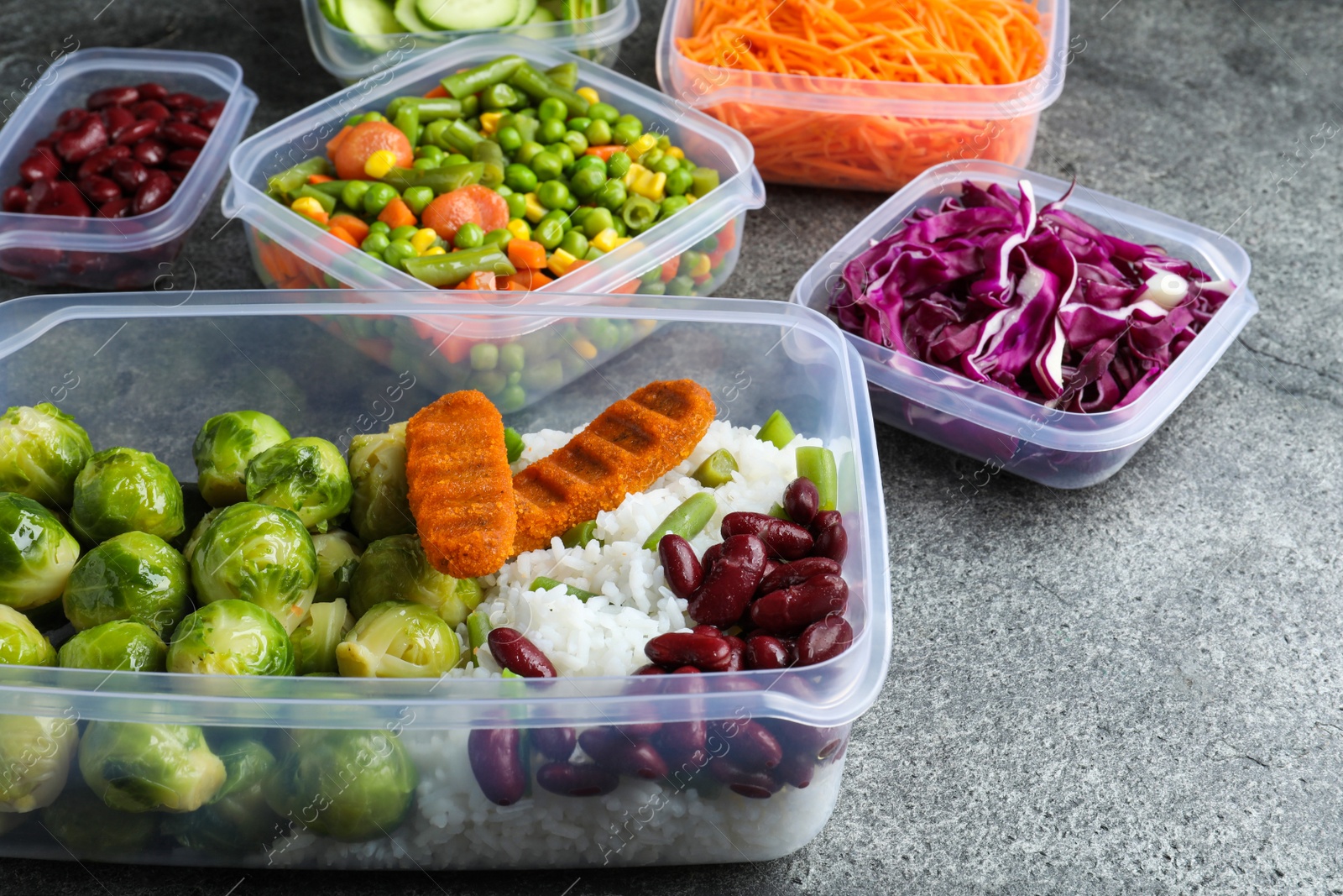 Photo of Set of plastic containers with fresh food on grey   table