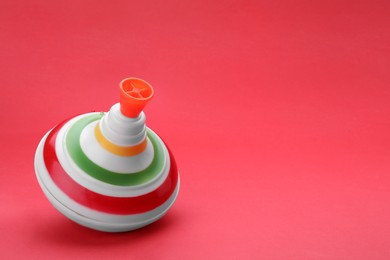 One bright spinning top on red background, space for text. Toy whirligig