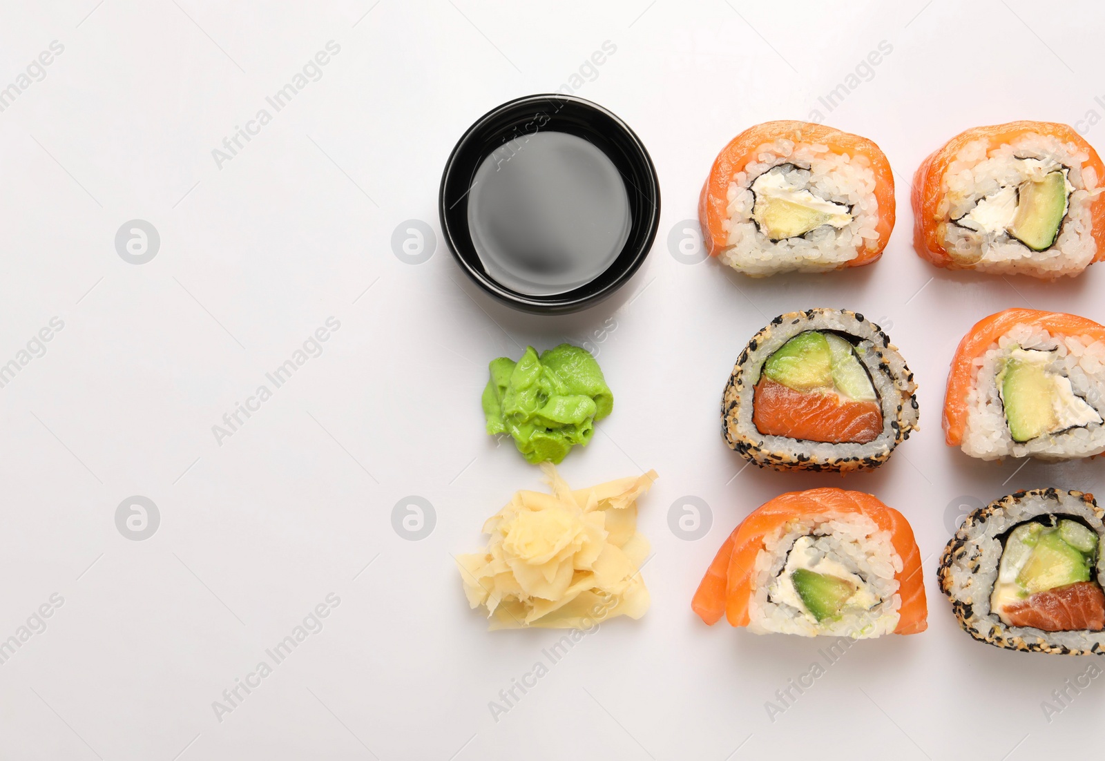 Photo of Delicious sushi rolls on white background, flat lay. Space for text