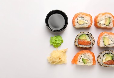 Photo of Delicious sushi rolls on white background, flat lay. Space for text