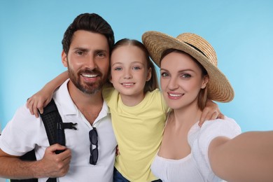 Happy family taking selfie on light blue background