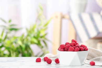 Photo of Bowl with ripe aromatic raspberries on table