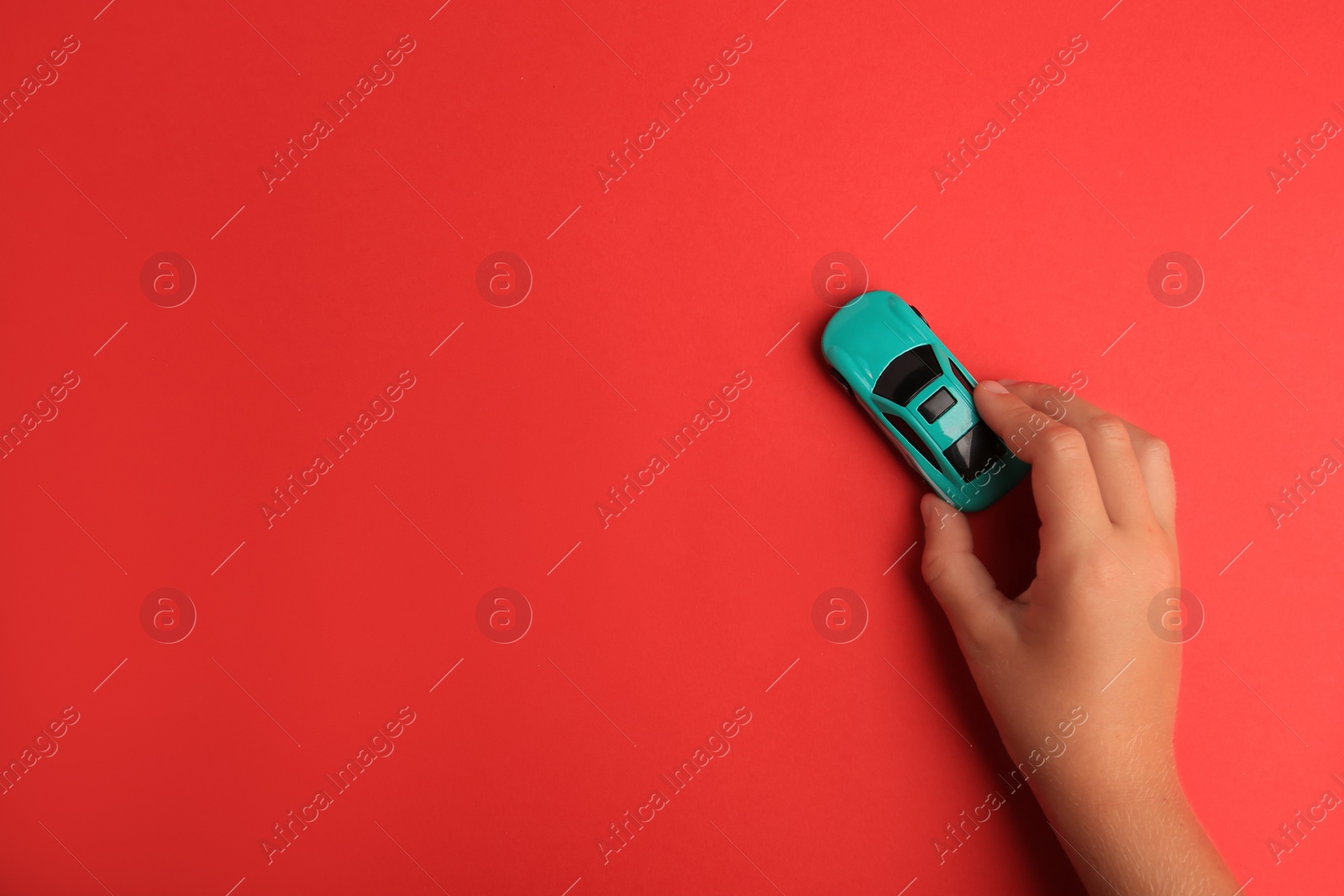 Photo of Child playing with toy car on red background, top view. Space for text