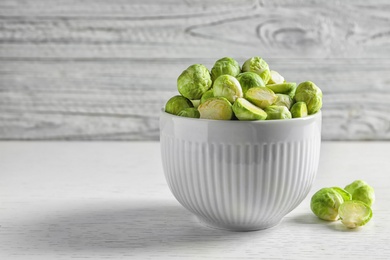 Photo of Bowl of fresh Brussels sprouts on table against wooden background. Space for text