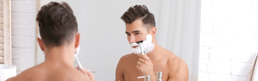 Image of Young man shaving near mirror in bathroom. Banner design