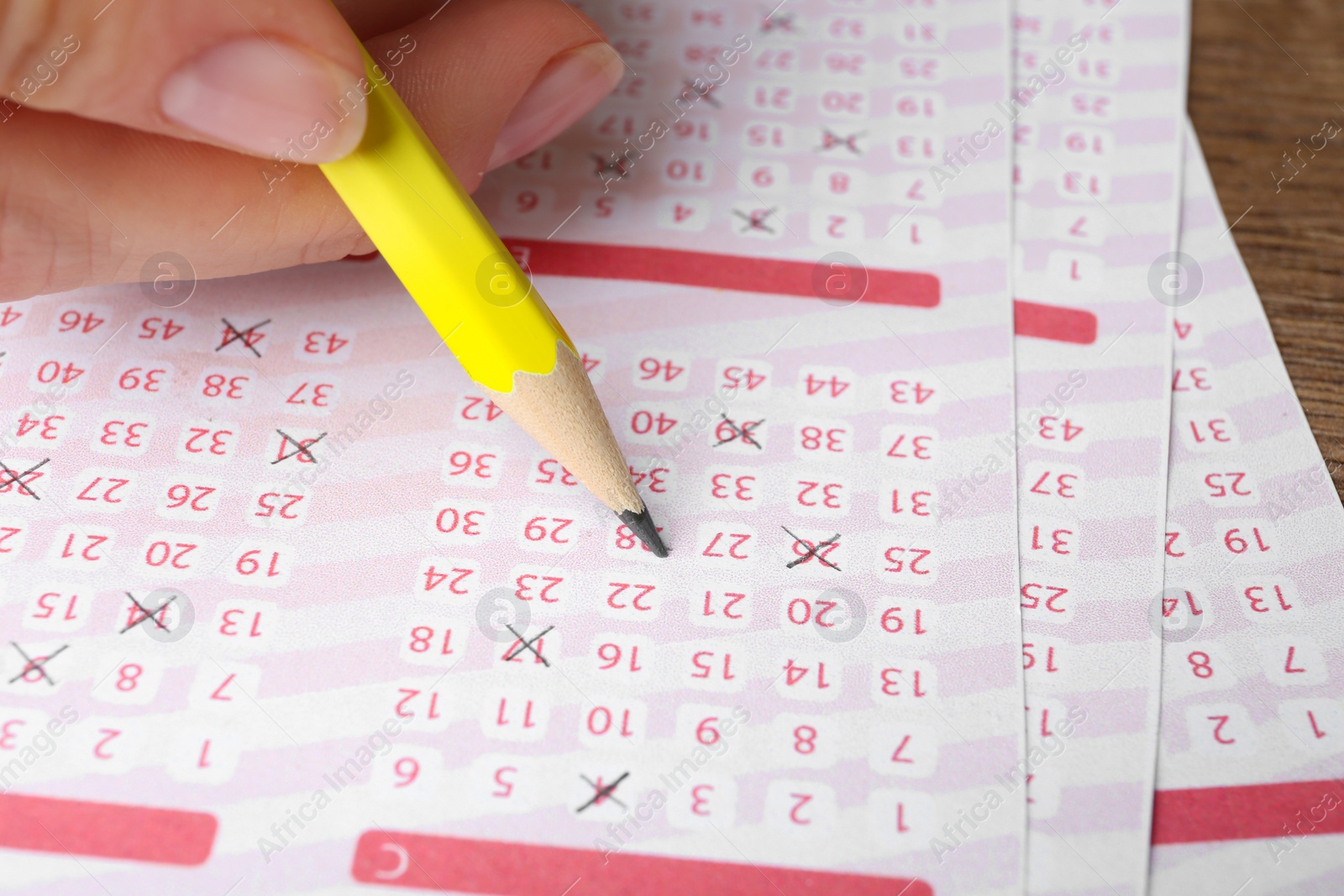 Photo of Woman filling out lottery tickets on wooden table, closeup. Space for text