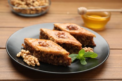 Photo of Delicious honey baklava with walnuts on wooden table, closeup