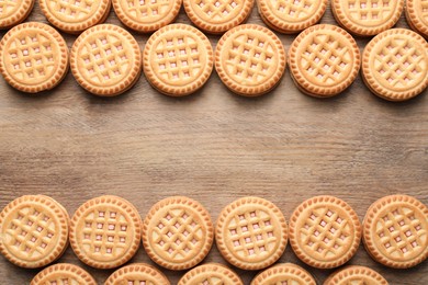 Tasty sandwich cookies with cream on wooden table, flat lay. Space for text