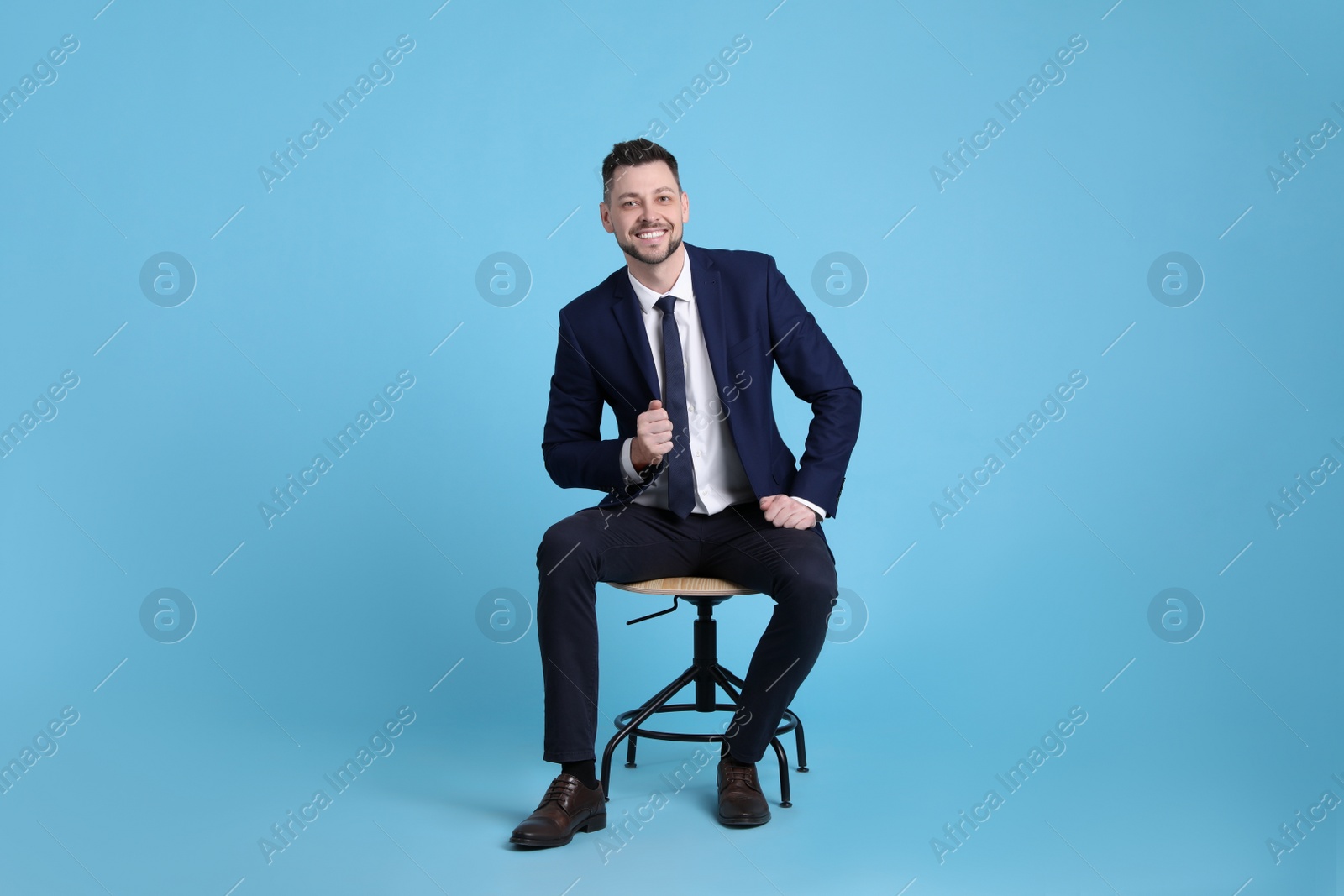 Photo of Handsome businessman sitting in office chair on light blue background