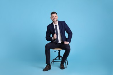 Photo of Handsome businessman sitting in office chair on light blue background