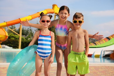 Photo of Cute little children with inflatable ring near pool in water park