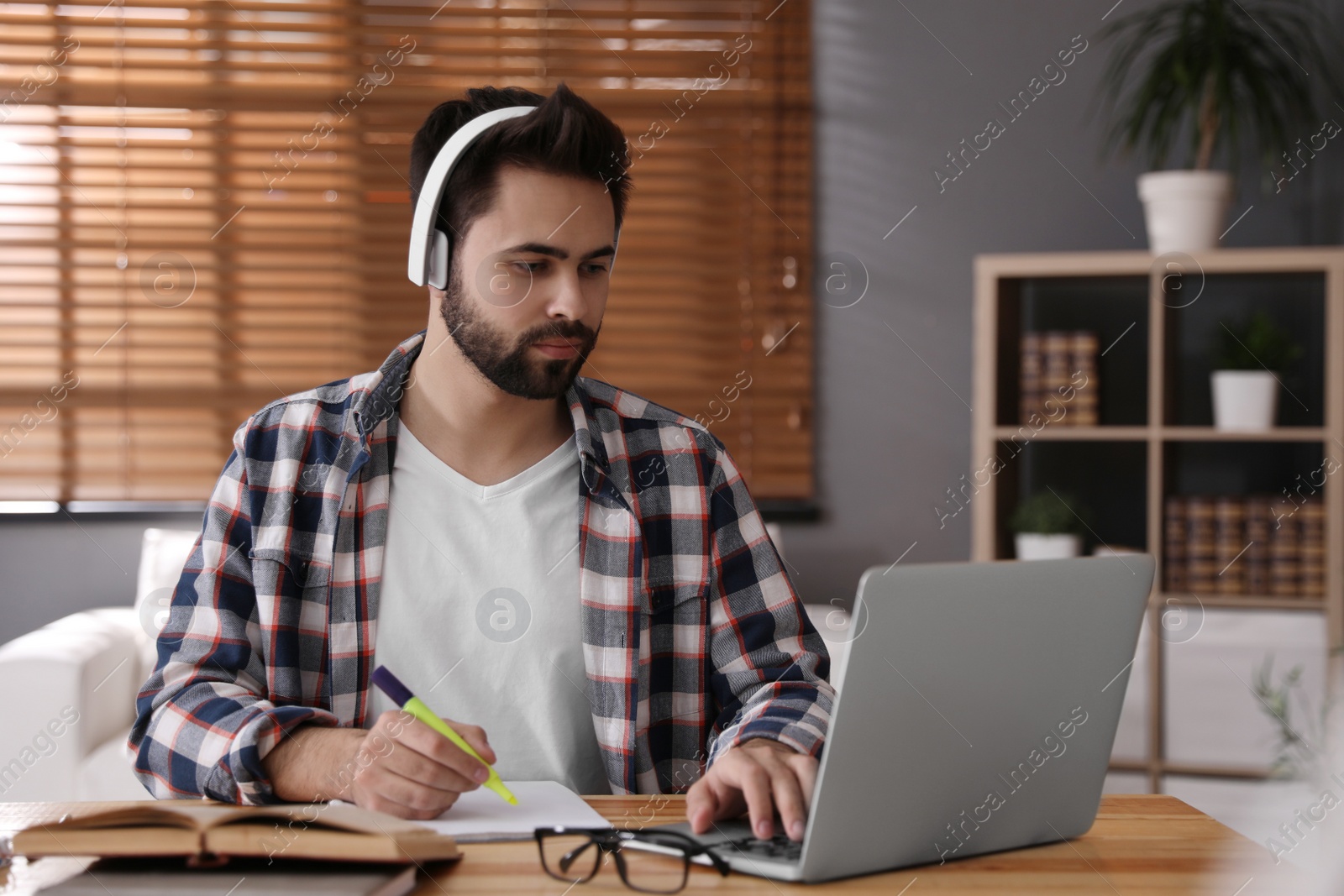 Photo of Young man watching webinar at table in room