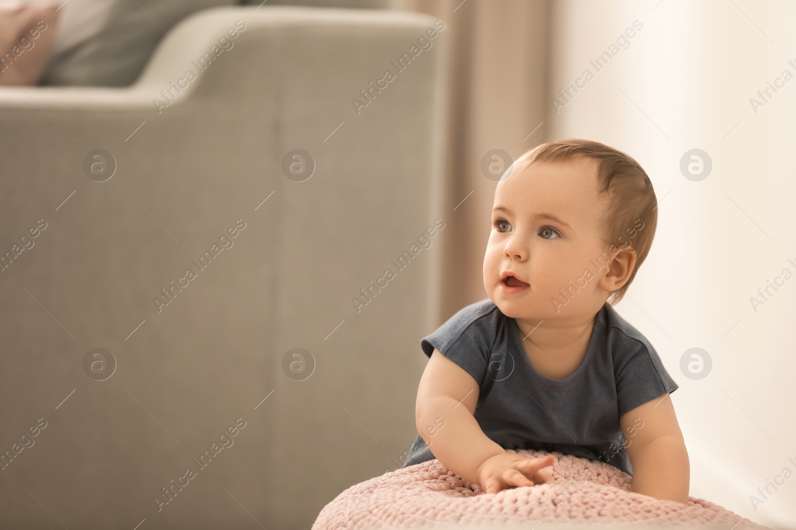 Photo of Cute baby holding on to pouf in living room. Learning to walk