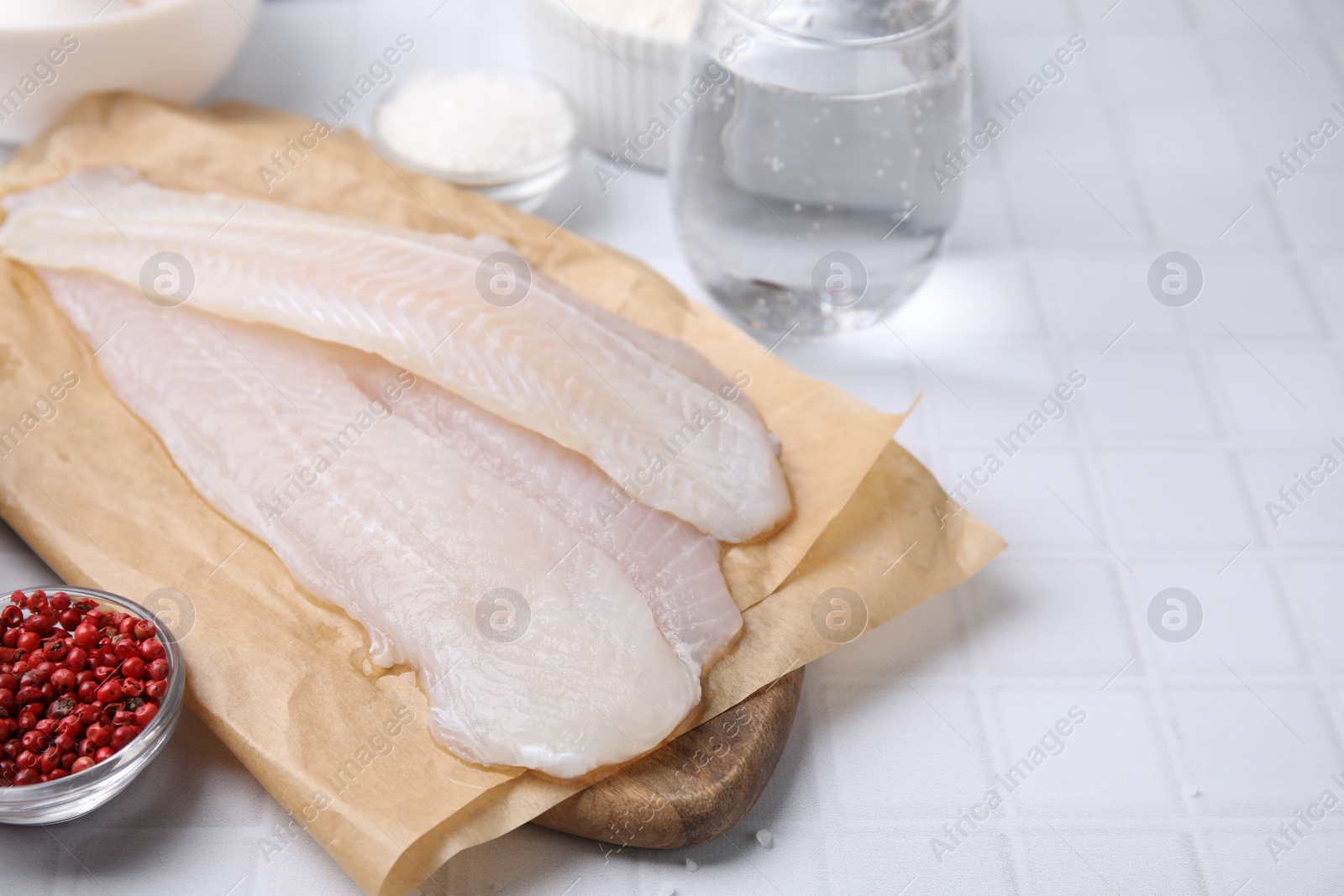 Photo of Different ingredients for soda water batter and raw fish fillet on white tiled table. Space for text