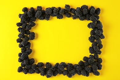 Frame made of tasty blackberries on yellow background, top view with space for text