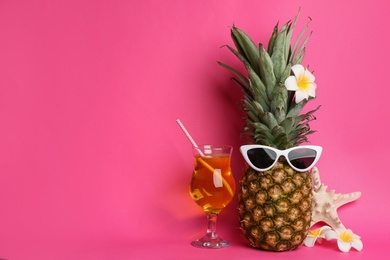 Funny pineapple with cocktail, plumeria flowers and starfish on pink background, space for text. Creative concept