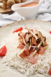 Photo of Delicious rice with bacon, mushrooms and tomatoes on plate, closeup