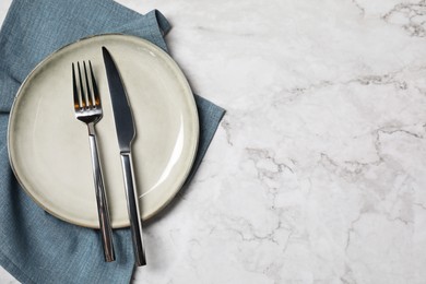 Stylish setting with elegant cutlery on white marble table, top view. Space for text