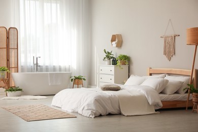 Photo of Stylish apartment interior with white bathtub and bed