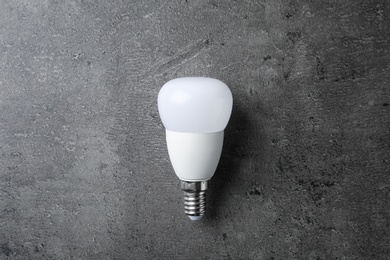 Photo of New modern lamp bulb on grey stone surface, top view