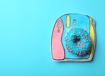 Photo of Camera made with donut on light blue background, top view. Space for text