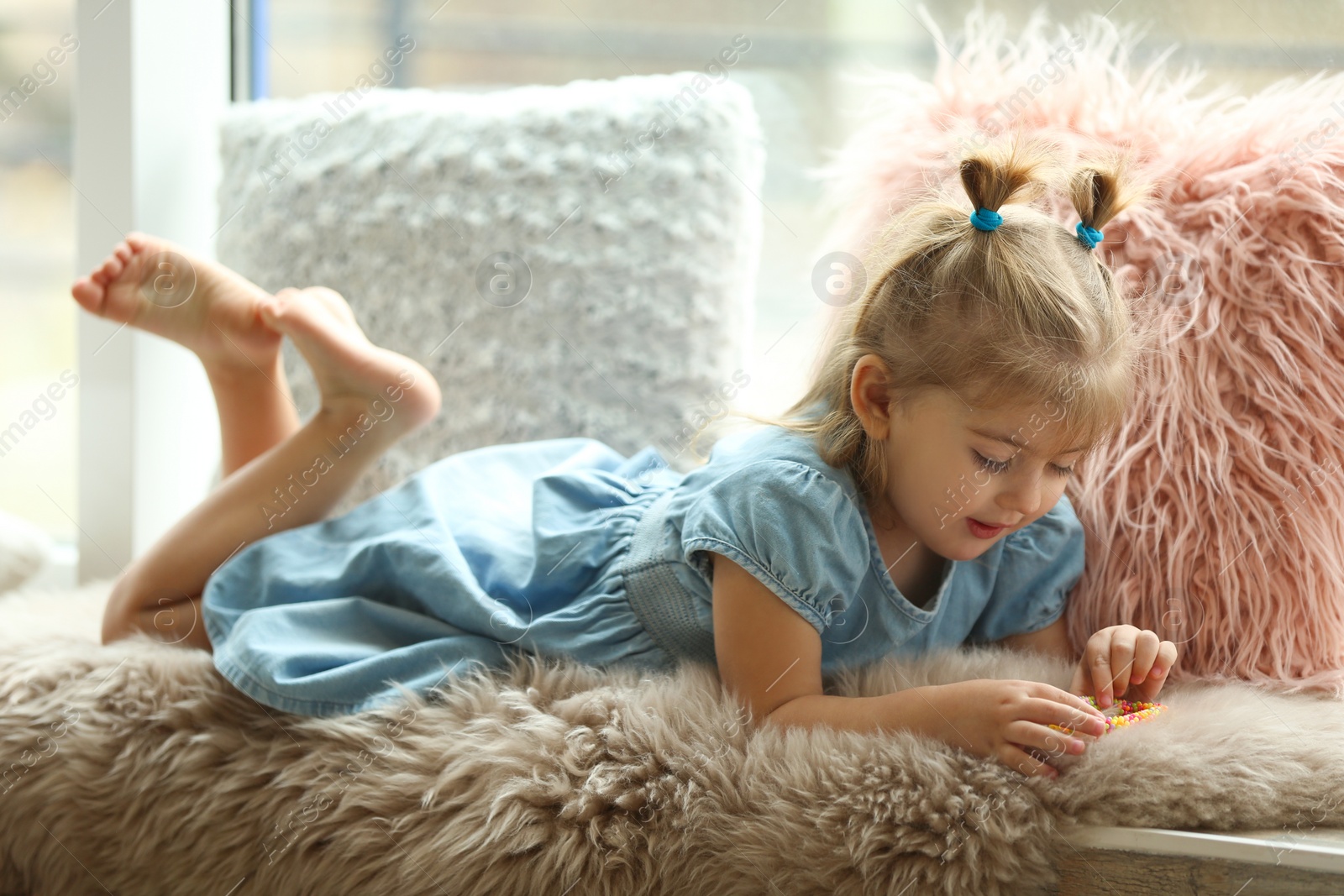 Photo of Cute little girl lying on fur plaid at home