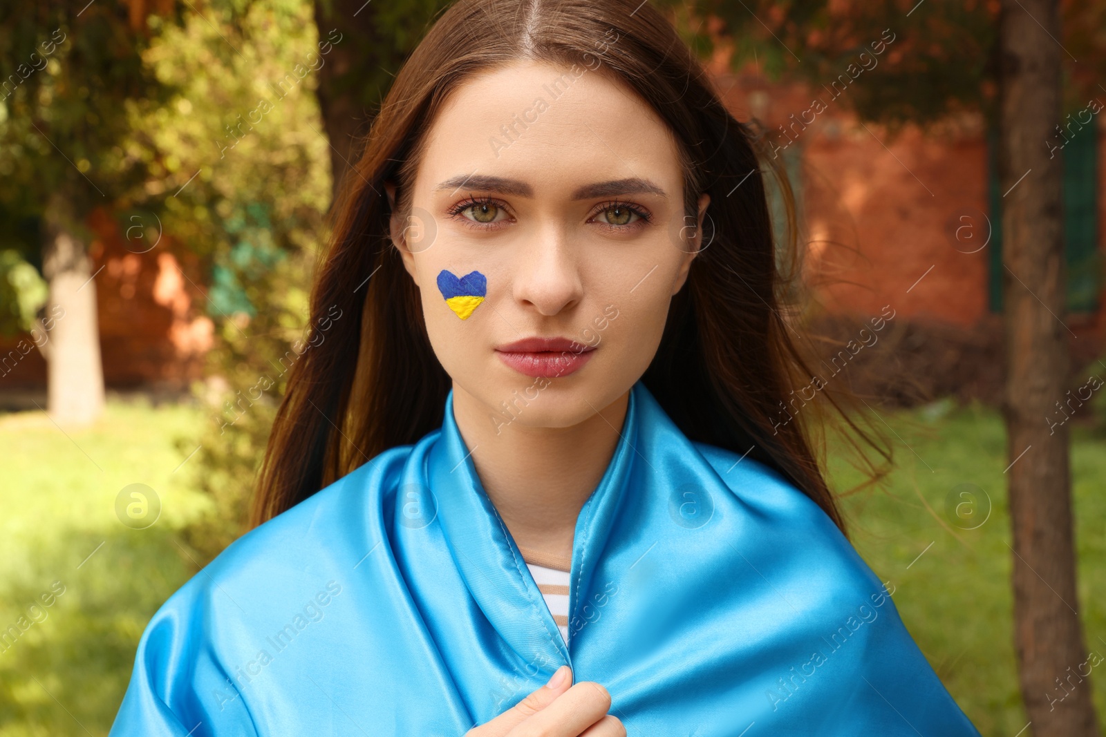 Photo of Young beautiful woman with Ukrainian flag in park