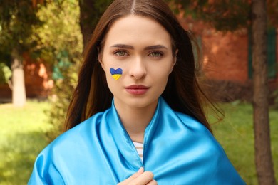 Photo of Young beautiful woman with Ukrainian flag in park