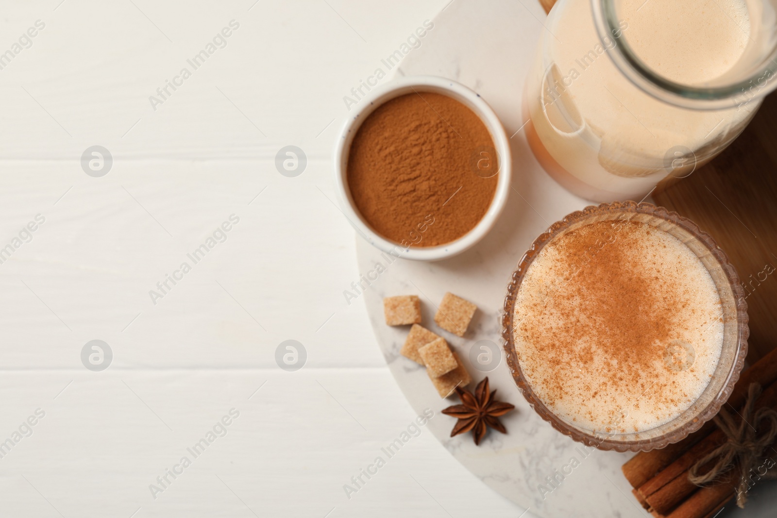 Photo of Delicious eggnog with anise and cinnamon on white wooden table, flat lay. Space for text