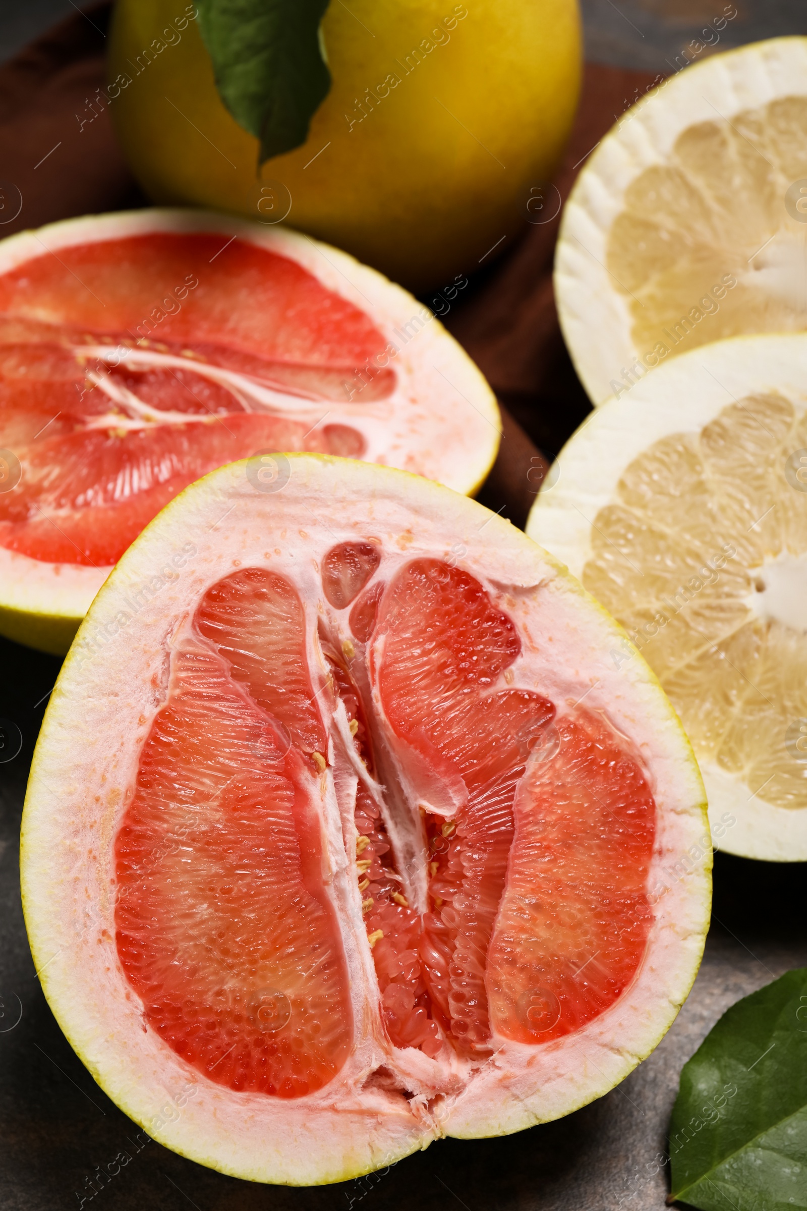 Photo of Fresh cut pomelo fruits with green leaves on dark table, closeup