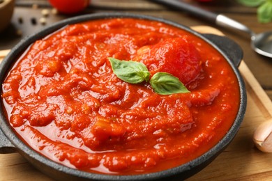 Photo of Homemade tomato sauce and basil in bowl on table, closeup