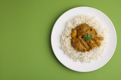 Photo of Delicious chicken curry with rice on green background, top view. Space for text