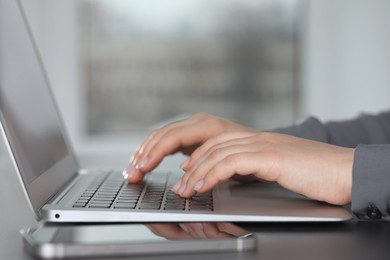 Photo of Woman typing on laptop at table, closeup. Electronic document management