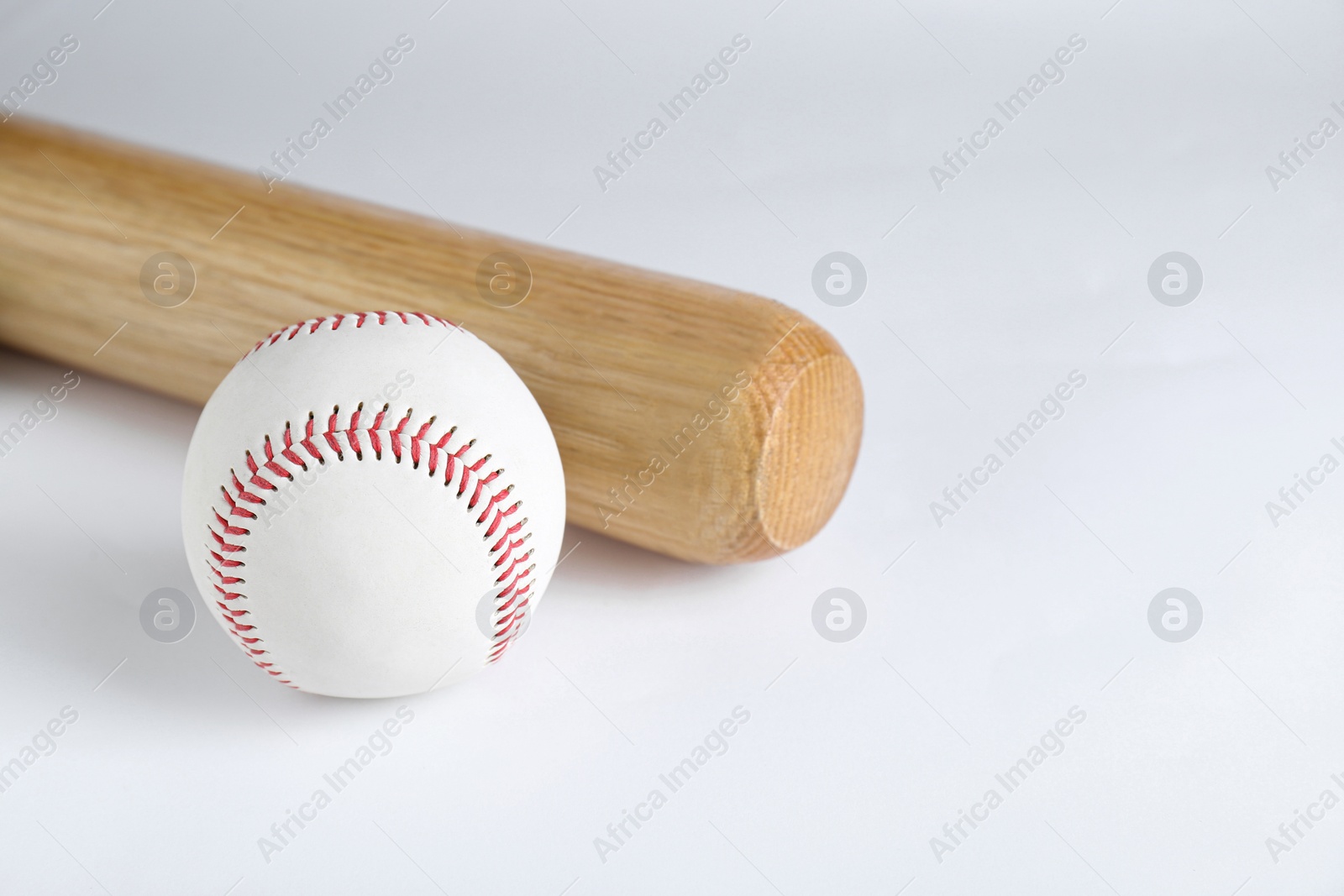 Photo of Wooden baseball bat and ball on white background. Sports equipment