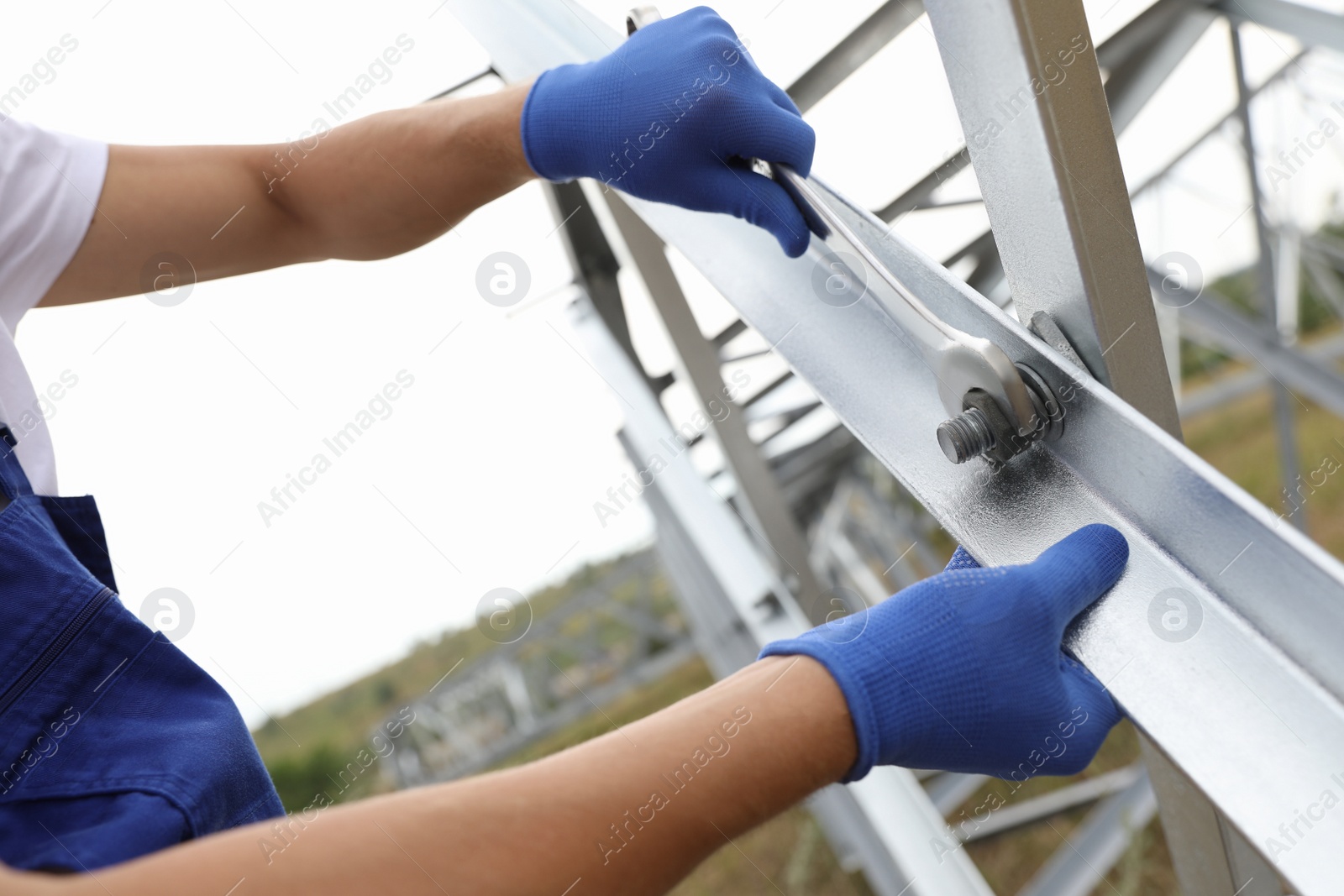 Photo of Worker building high voltage tower construction outdoors, closeup. Installation of electrical substation