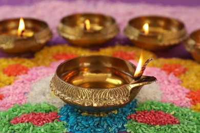 Diwali celebration. Diya lamps on colorful rangoli, closeup