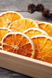 Photo of Crate of dry orange slices on wooden table, closeup