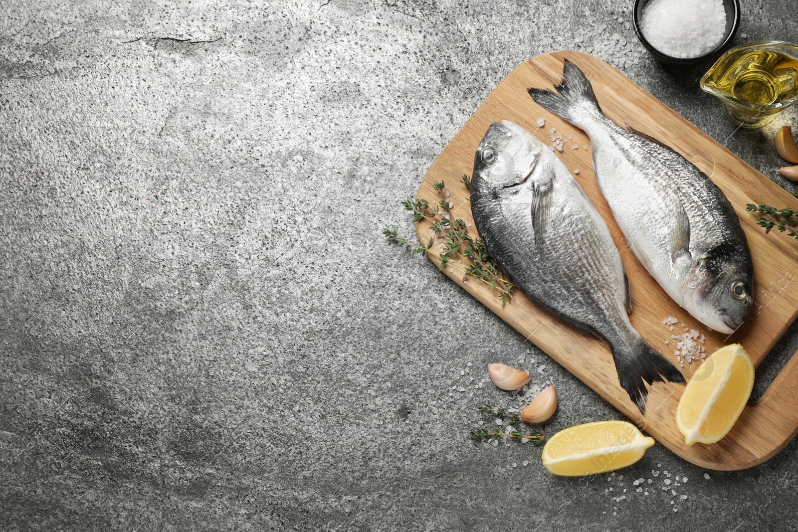 Photo of Flat lay composition with raw dorada fish on grey table, space for text