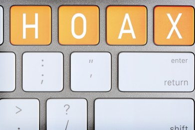 Orange buttons with letters making Hoax on computer keyboard, top view