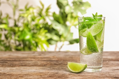 Refreshing beverage with mint and lime in glass on table