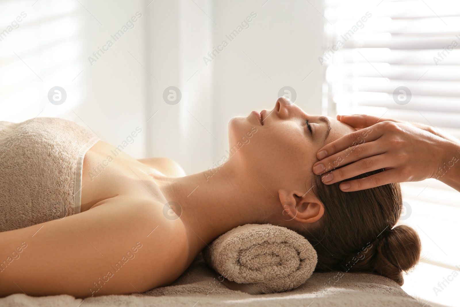 Photo of Young woman receiving head massage in spa salon