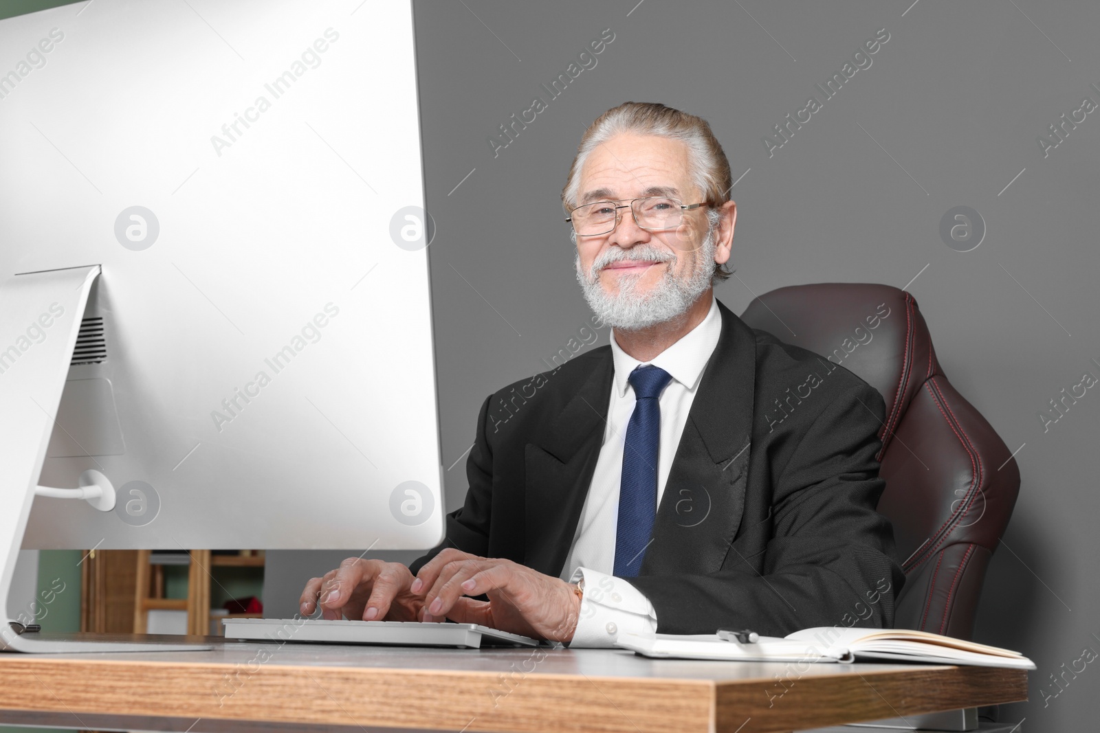 Photo of Happy senior boss working in his office