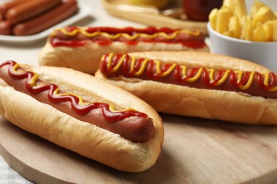 Photo of Fresh delicious hot dogs with sauces on wooden board, closeup