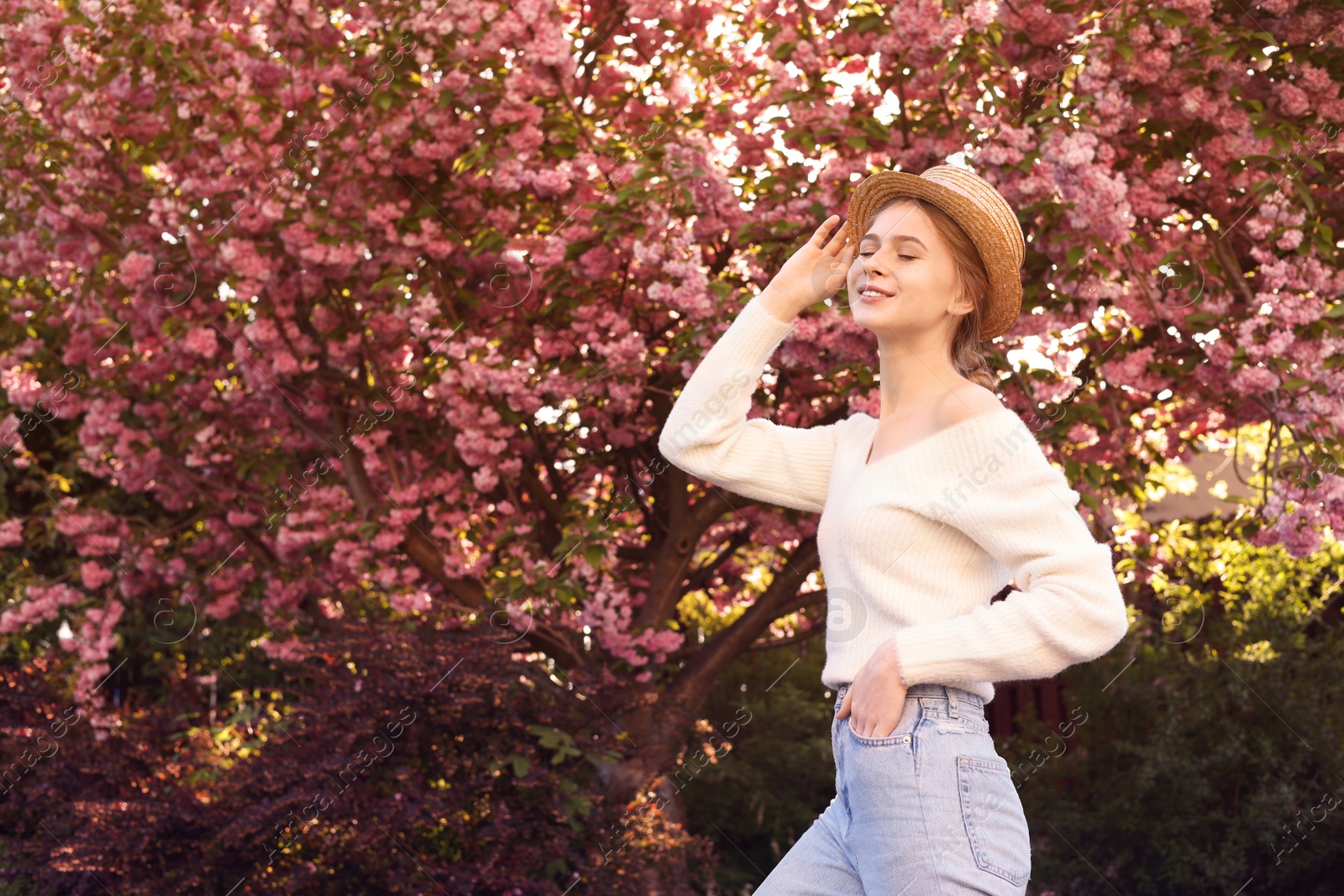 Photo of Beautiful teenage girl with hat near blossoming tree in spring