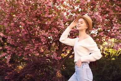 Beautiful teenage girl with hat near blossoming tree in spring