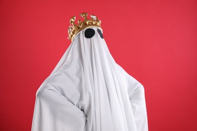 Photo of Person in ghost costume and luxurious crown on red background