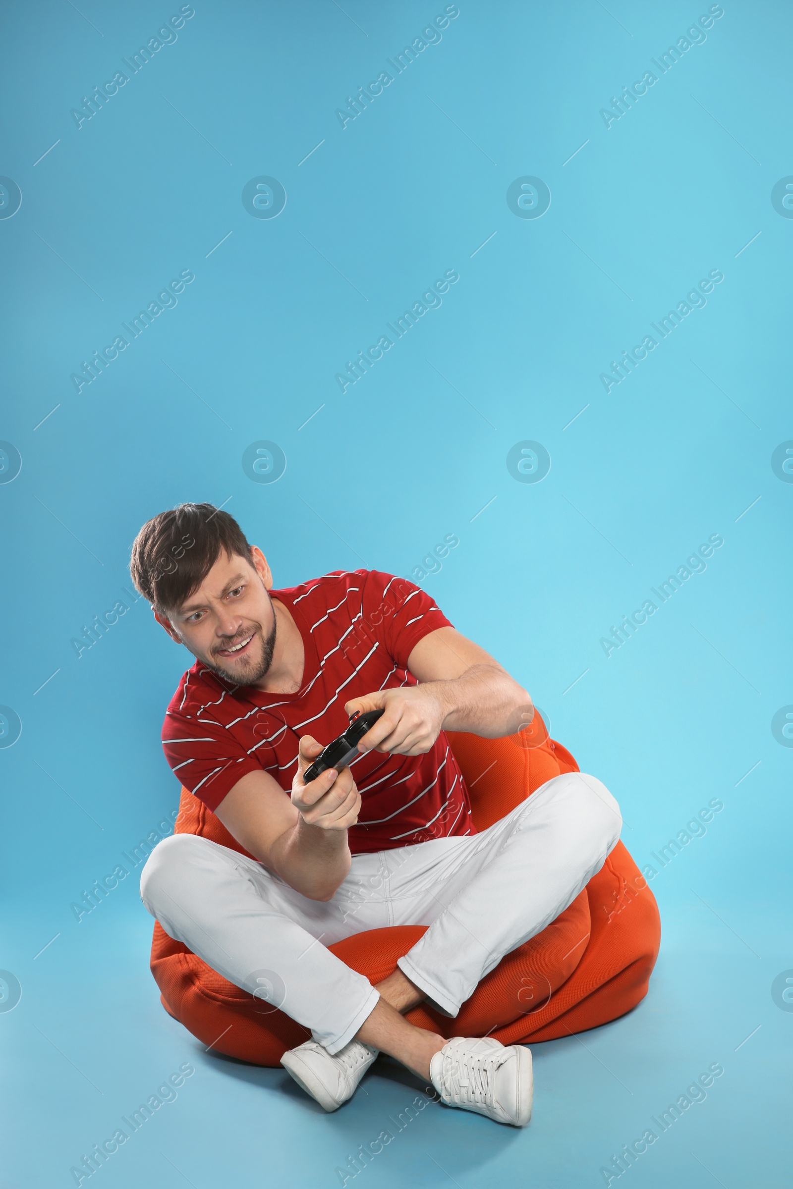 Photo of Emotional man playing video games with controller on color background. Space for text